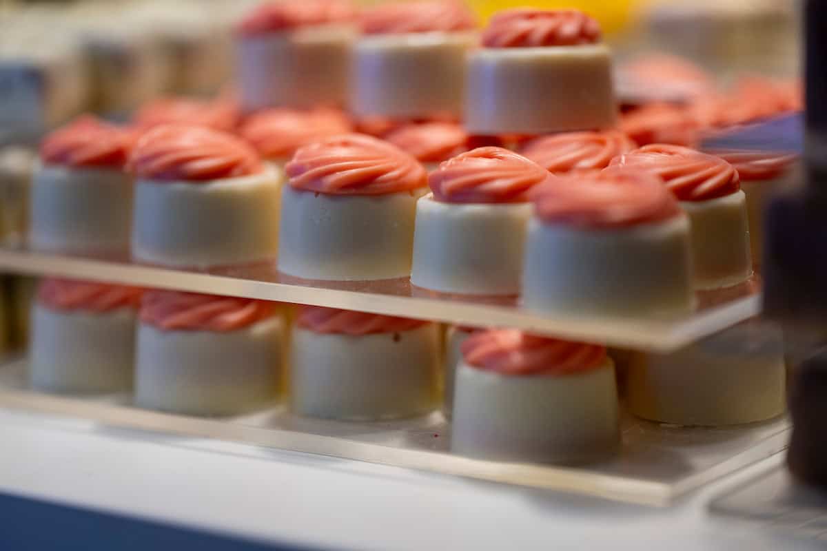 Delicate witte chocolade en roze glacering lekkernijen afgebeeld bij Koffie Thee Lokaal Delicious, perfect voor koffie en thee genieten.