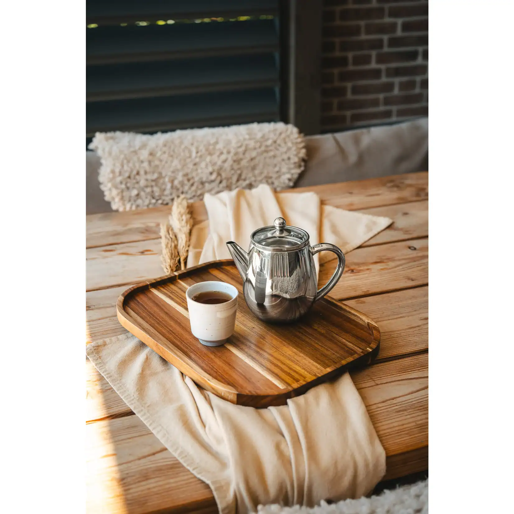 Stijlvolle theepot en kopje op houten dienblad, gezellige terrassetting bij De Heeren van 17, perfect voor ontspanning en genieten van een warm drankje.
