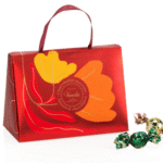 Zwarte theezakjes en een rood cadeaudoos met gele en oranje bloemprint, geschikt voor thee- en koffieliefhebbers, perfect voor geschenken of zelfgebruik bij Koffie Thee Lokaal Delicious.