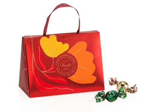 Zwarte theezakjes en een rood cadeaudoos met gele en oranje bloemprint, geschikt voor thee- en koffieliefhebbers, perfect voor geschenken of zelfgebruik bij Koffie Thee Lokaal Delicious.