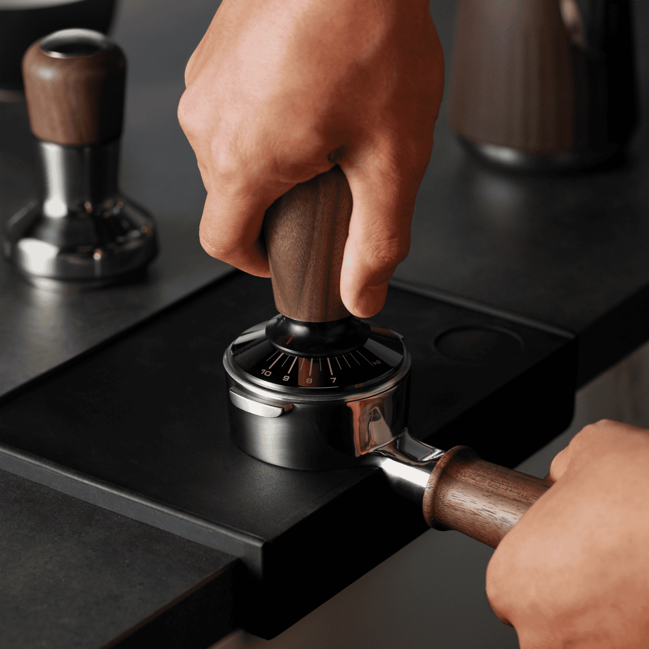 Zwarte espressomachine met hand die de koffiemolen bedient, in een koffie- en theelokaal, focus op versgemalen koffie, ambachtelijke koffiezetten, en koffie-ervaring.