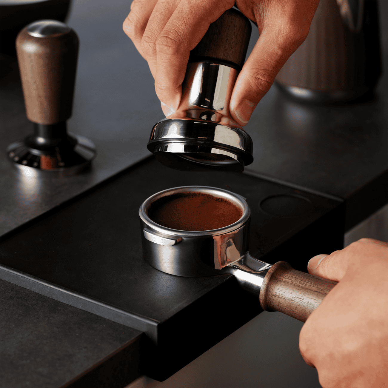Een barista bereidt verse espresso met een handmatige koffiemolen en een espressomachine, in een gezellige koffie- en theelokaal. Perfect voor koffieliefhebbers die genieten van ambachtelijke koffie.