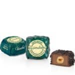 Drie chocoladebonbons, inclusief een met een hazelnootvulling, gepresenteerd op een witte achtergrond, perfect voor koffie- en theeliefhebbers.