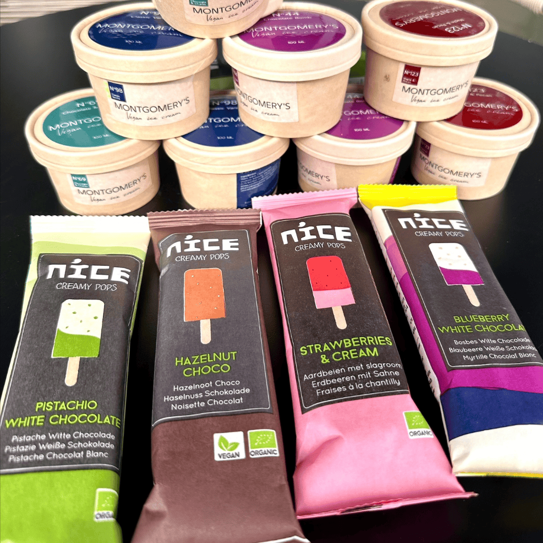 Een assortiment van veganistische ijsjes met verschillende smaken zoals pistache, hazelnoot, aardbeien en blauwe bessen, gepresenteerd op een tafel.