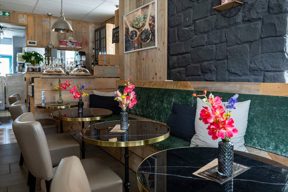Koffie- en theelokaal Delicious met gezellige zitplaatsen, bloemen en een moderne inrichting, ideaal voor een ontspannen koffie- of theemoment in een sfeervolle omgeving.
